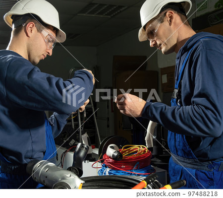 Engineers arrange new charging plug in equipped workshop Engineers arrange new charging plug in equipped workshop 97488218