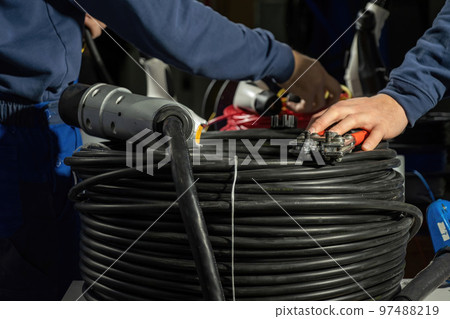 Electricians install cables in plug to charge EV on stations Electricians install cables in plug to charge EV on stations 97488219