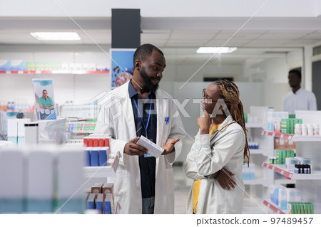 African american pharmacist consulting buyer in pharmaceutical drugstore, woman choosing medications, buying supplements. Pharmacy consultant and client discussing vitamins prescription African american pharmacist consulting buyer in pharmaceutical drugstore, woman choosing medications, buying supplements. Pharmacy consultant and client discussing vitamins prescription 97489457