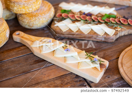 Delicious cheese slices served with rosemary sprouts and flowers on wooden cutting board 97492549