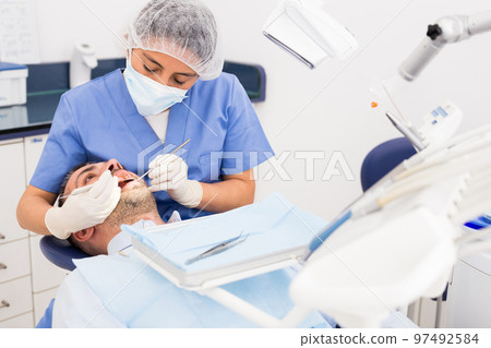 Female dentist in face mask with male patient 97492584