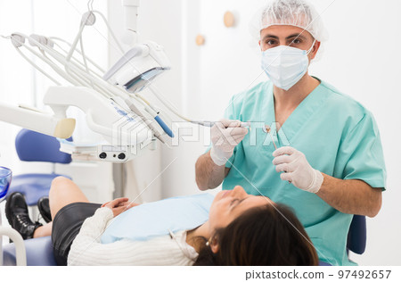 Male dentist drilling tooth to female patient 97492657