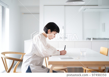 年輕女子在房間裡的筆記本上寫字 97498350