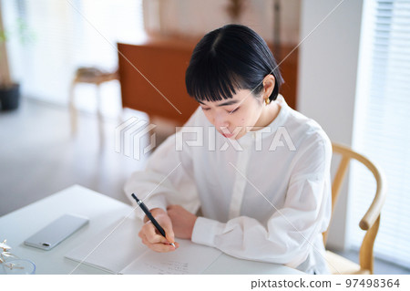 年輕女子在房間裡的筆記本上寫字 97498364