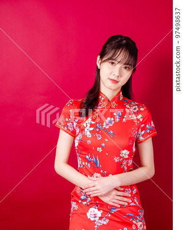Portrait of young asian woman in traditional cheongsam have stomach ache isolated over red background 97498637