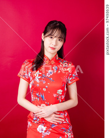 Portrait of young asian woman in traditional cheongsam have stomach ache isolated over red background 97498639