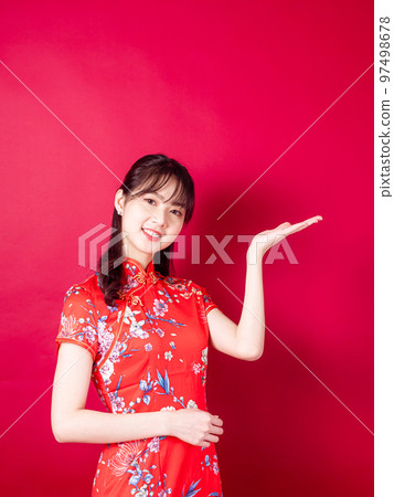 身穿傳統旗袍的亞洲年輕女性,在紅色背景中以介紹的姿態孤立。 身穿傳統旗袍的亞洲年輕女性,在紅色背景中以介紹的姿態孤立。 97498678
