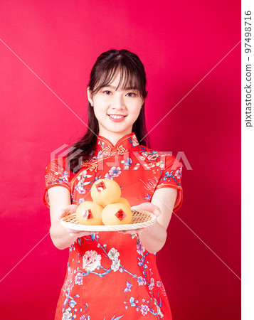 Young asian woman in traditional cheongsam man with small chinese festival couplet meaning good luck on red background 97498716