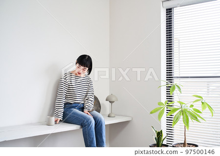 A woman relaxing in a room with houseplants 97500146