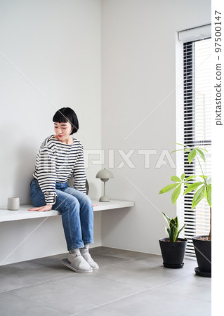 A woman relaxing in a room with houseplants 97500147