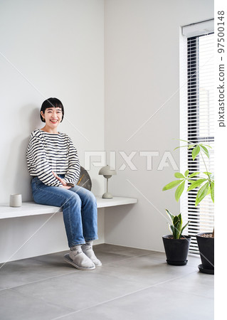 A woman relaxing in a room with houseplants 97500148