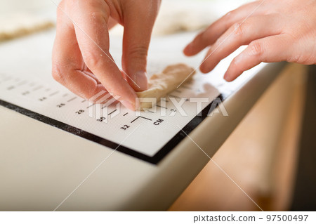 Close-up on a kitchen silicone baking mat with markings as a helper in the kitchen and the hands of a cook, copy space 97500497