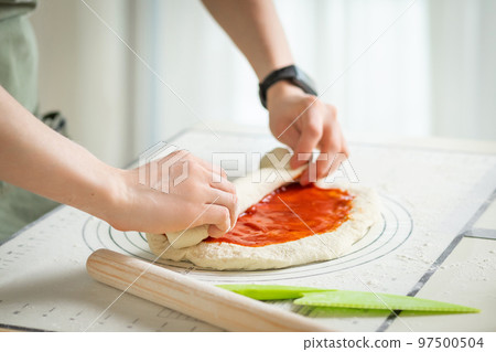 The cook is cooking a sweet roll with strawberry jam on a white silicone baking mat 97500504