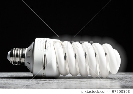 Glowing fluorescent bulb light on the grey table on black background 97500508