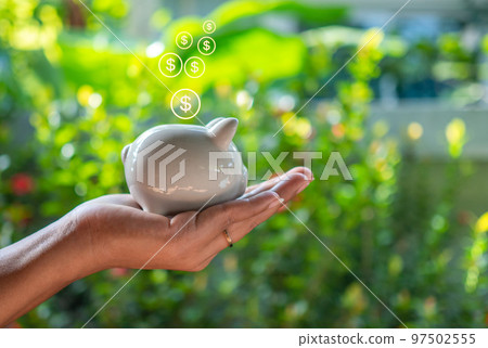 Hand human and Piggy bank on natural bokeh background. saving concept Hand human and Piggy bank on natural bokeh background. saving concept 97502555