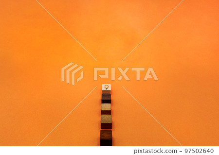 An orange background with an idea and a light bulb lit on top of a wood cube 97502640