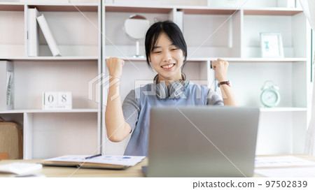 Joyful, Surprised or shocked Asian woman raised her arms all the way because she did a good job the boss gave her a big bonus making her very happy, Raise your hand, Smiling and screaming for success. 97502839