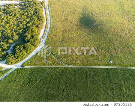 Aerial view on green wheat field in countryside. Field of wheat blowing in the wind on sunset. Young and green Spikelets. Ears of barley crop in nature. Agronomy, industry and food production. Aerial view on green wheat field in countryside. Field of wheat blowing in the wind on sunset. Young and green Spikelets. Ears of barley crop in nature. Agronomy, industry and food production. 97505156