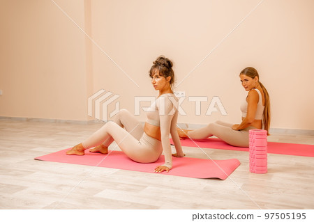 Well looking middle aged womans, fitness instructor in beige sportswear, preparing for stretching and pilates on yoga mat in the gym. Female fitness yoga concept. Healthy lifestyle harmony, meditation Well looking middle aged womans, fitness instructor in beige sportswear, preparing for stretching and pilates on yoga mat in the gym. Female fitness yoga concept. Healthy lifestyle harmony, meditation 97505195