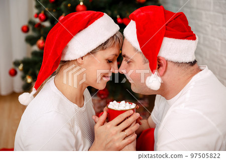 Cute young couple drinking hot chocolate on Christmas eve at home. 97505822