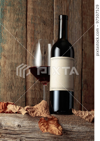 Bottle and glass of red wine on an old wooden table. Bottle and glass of red wine on an old wooden table. 97507529