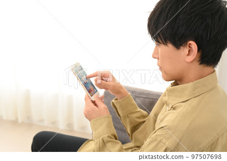 坐在沙發上使用智能手機的男人 97507698