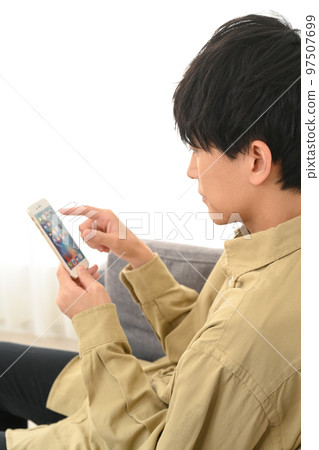 坐在沙發上使用智能手機的男人 97507699