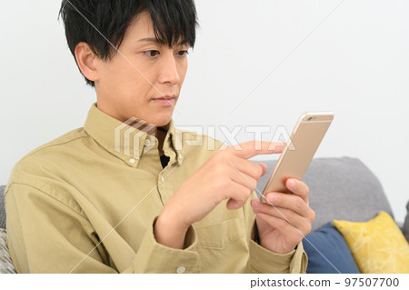 坐在沙發上使用智能手機的男人 97507700