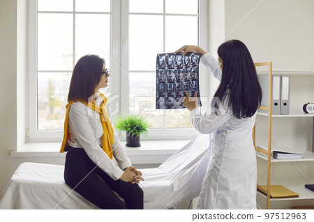 Female doctor showing radiography to her patient in medical office Female doctor showing radiography to her patient in medical office 97512963