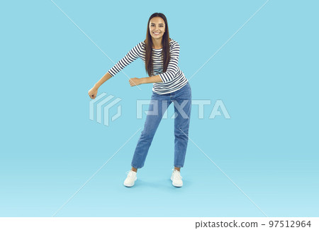 Young woman in casual clothes doing funny floss dancing move on blue studio background Young woman in casual clothes doing funny floss dancing move on blue studio background 97512964