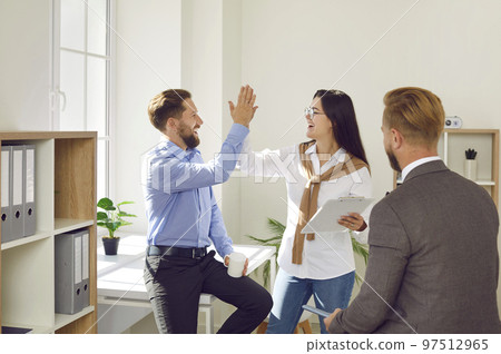 Excited couple give high five closing deal with real estate agent Excited couple give high five closing deal with real estate agent 97512965