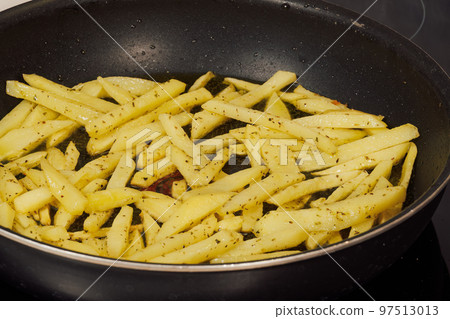 Frying French fries in hot olive oil at home kitchen close up. 97513013