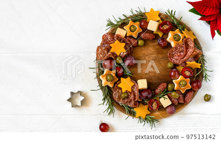 Christmas appetizers wreath wooden cutting board and white wooden table with copy space of text 97513142