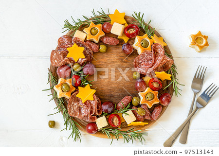 Christmas charcuterie board made in wreath shape on wooden cutting board and white wooden table Christmas charcuterie board made in wreath shape on wooden cutting board and white wooden table 97513143