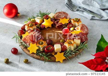 Christmas appetizers wreath on wooden board and grey background, star of Christmas plant or Poinsettia, napkin, forks Christmas appetizers wreath on wooden board and grey background, star of Christmas plant or Poinsettia, napkin, forks 97513145