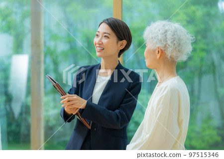 A woman in a suit showing a property to a senior woman 97515346