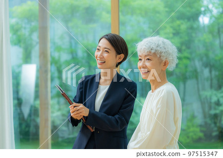 A woman in a suit showing a property to a senior woman 97515347