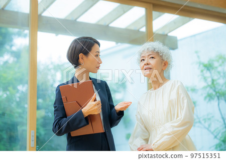 一位穿西裝的女士向一位資深女士展示房產 97515351