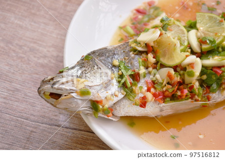 steamed bass fish dressing lemon sweet and sour chili sauce on plate  97516812