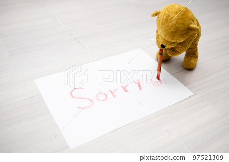 A stuffed bear that writes Sorry on paper with a crayon. 97521309