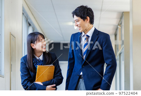Male and female high school students in uniforms walking in the corridor Male and female high school students in uniforms walking in the corridor 97522404