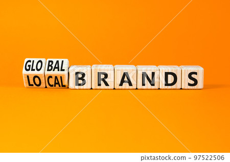 Global or local brands symbol. Concept words Global brands and Local brands on wooden cubes. Beautiful orange table orange background. Business global or local brand concept. Copy space. Global or local brands symbol. Concept words Global brands and Local brands on wooden cubes. Beautiful orange table orange background. Business global or local brand concept. Copy space. 97522506