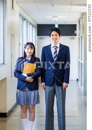 Male and female high school students in uniforms walking in the corridor 97522550
