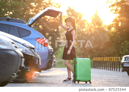 Young female driver putting luggage suitcase bag inside her car. Travelling and vacations concept Young female driver putting luggage suitcase bag inside her car. Travelling and vacations concept 97525544