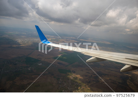 View of jet airplane wing landing at airport in bad weather. Travel and air transportation concept. View of jet airplane wing landing at airport in bad weather. Travel and air transportation concept. 97525679