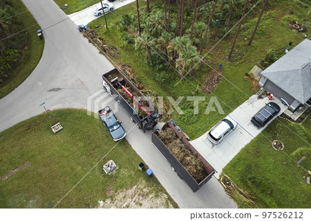 Top view of Hurricane Ian special aftermath recovery dump truck picking up tree branches debris from Florida rural streets. Dealing with consequences of natural disaster 97526212