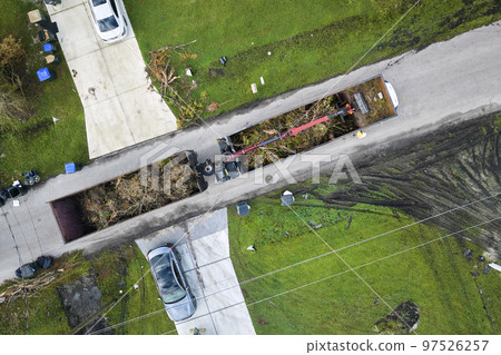Special aftermath recovery dump truck picking up vegetation debris from suburban streets after hurricane Ian swept through Florida. Dealing with consequences of natural disaster 97526257