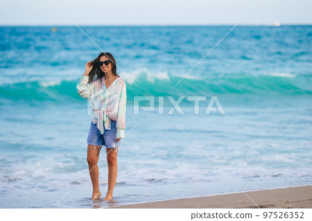 Young happy woman walking on the beach Young happy woman walking on the beach 97526352