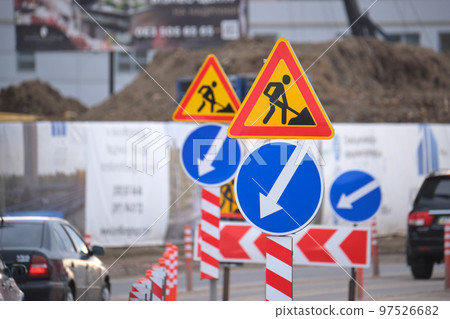Roadworks warning traffic signs of construction work on city street and slowly moving cars Roadworks warning traffic signs of construction work on city street and slowly moving cars 97526682