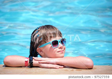 Happy child girl relaxing on swimming pool side on sunny summer day Happy child girl relaxing on swimming pool side on sunny summer day 97527359
